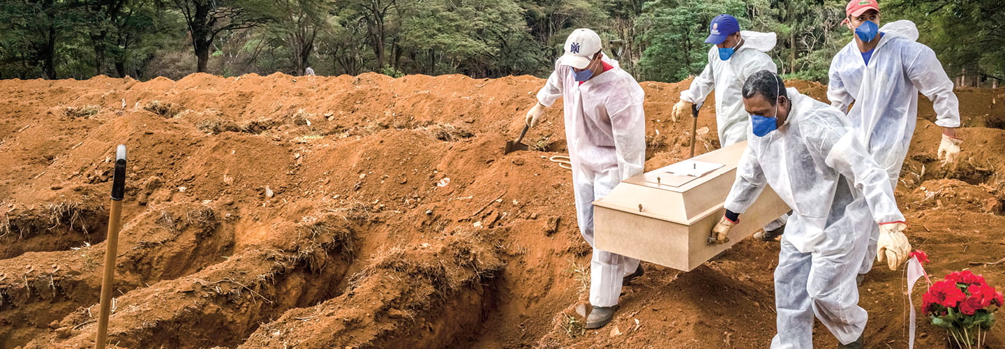 Four men wearing hazmat suits and masks carrying a casket to bury it