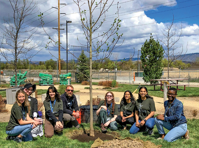 Enlargeable photo of volunteers gathered around a tree they planted