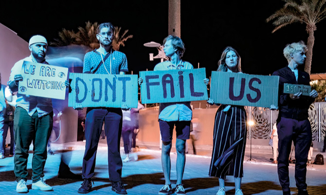 Enlargeable photo of climate change protesters with signs that read, "We&apos;re watching: Don&apos;t Fail Us"