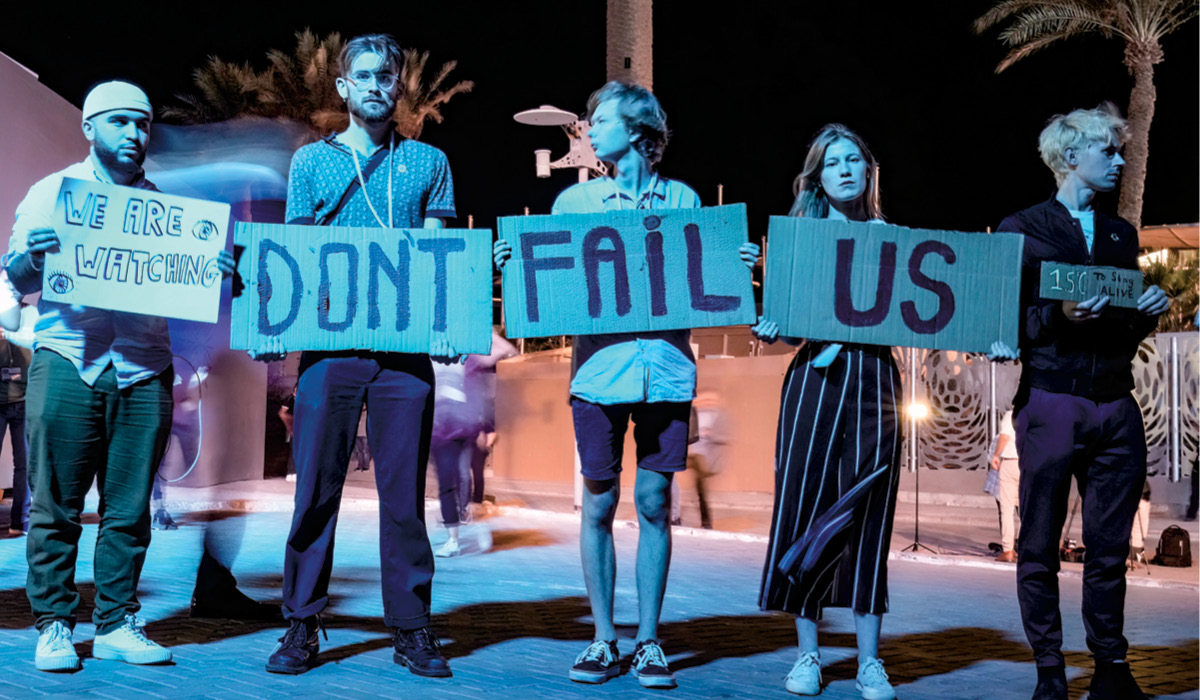 Photo of climate change protesters with signs that read, "We&apos;re watching: Don&apos;t Fail Us"