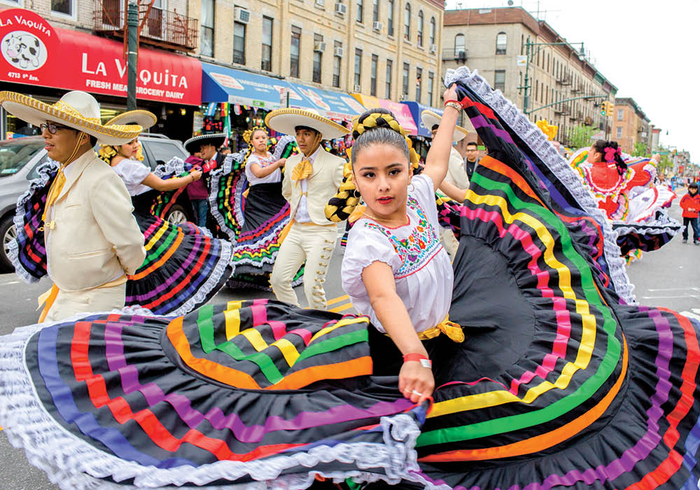 People wearing cultural clothing and dancing in the city streets