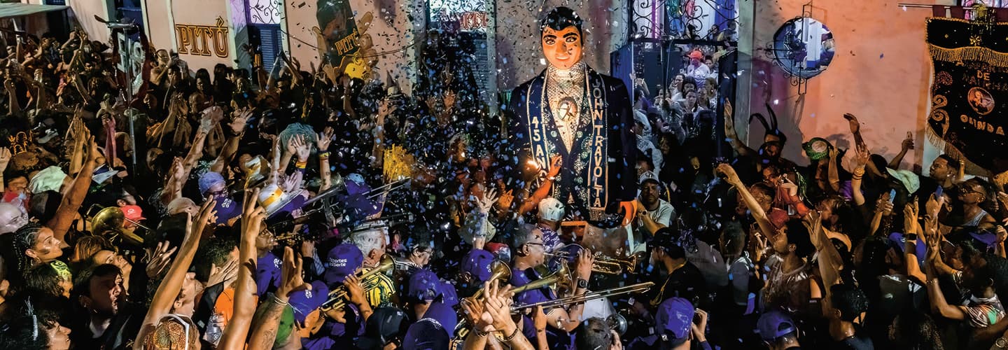 Image of people celebrating a John Travolta statue with music and confetti